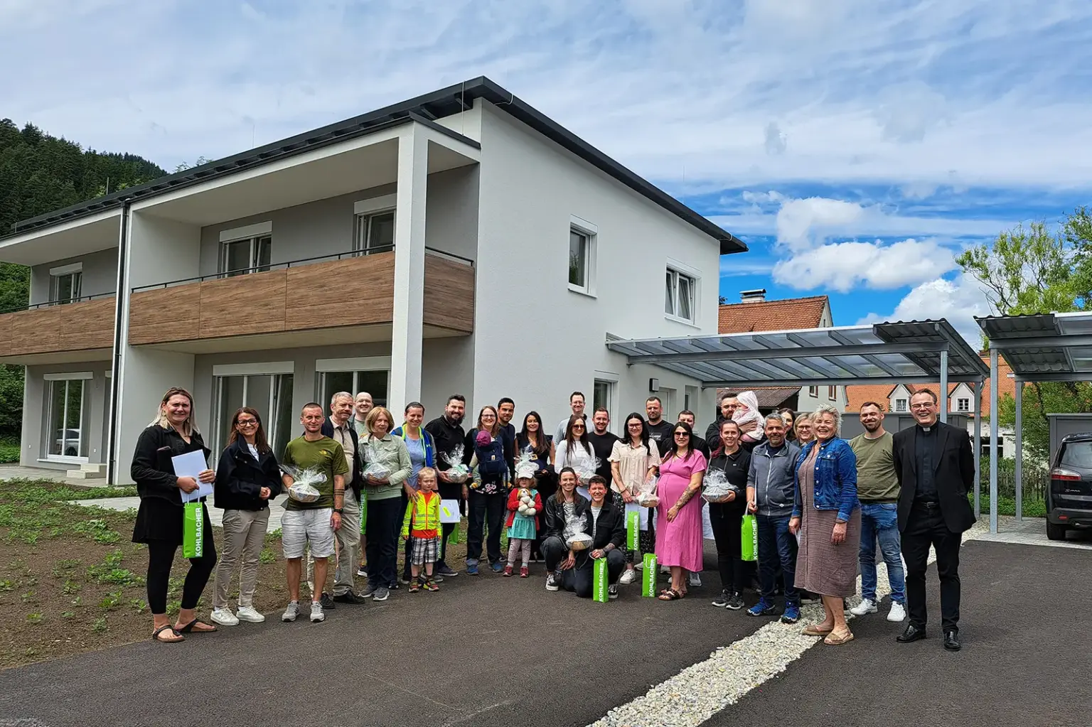 Pernegg: Hausübergabe an 14 Familien Eine große Gruppe von Personen steht vor einem Haus