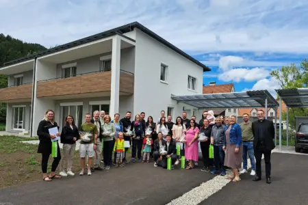 Pernegg: Hausübergabe an 14 Familien Eine große Gruppe von Personen steht vor einem Haus