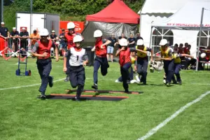 Eine Gruppe Jugendlicher in Uniformen und Helmen läuft über eine Wiese