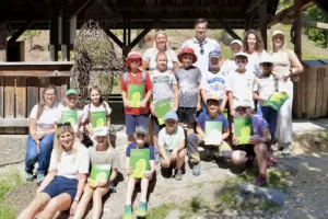 Eine Gruppe von Kindern posiert mit einigen Erwachsenen vor einem Holzverschlag