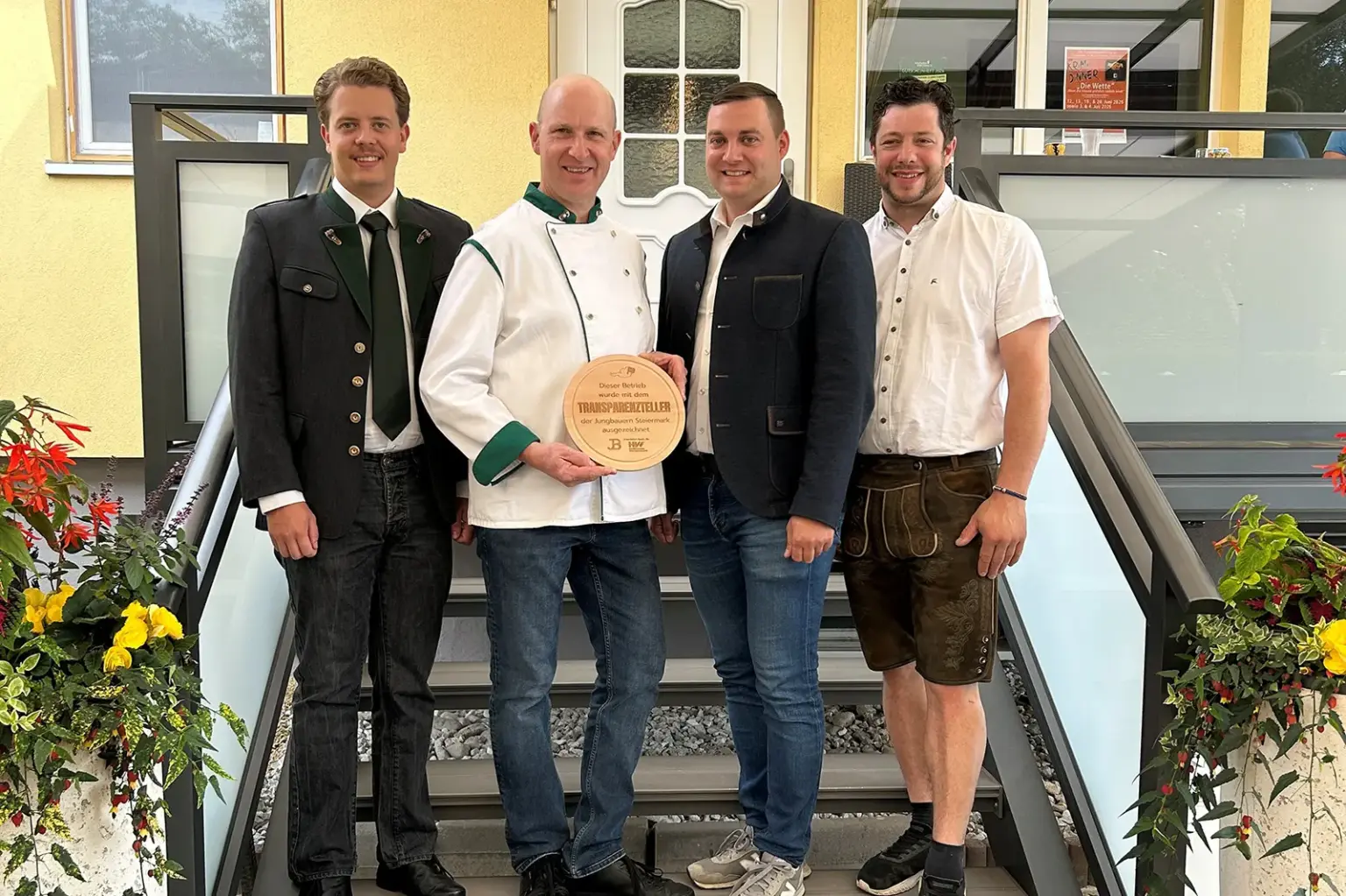 Auszeichnung für Gastronom aus St. Peter-Freienstein Vier Männer stehen mit einer Plakette auf einer Treppe vor einem Haus