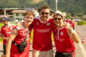 Drei junge Männer in roten Trikots der „Wanderfreunde Langenwang“ posieren gut gelaunt für die Kamera.