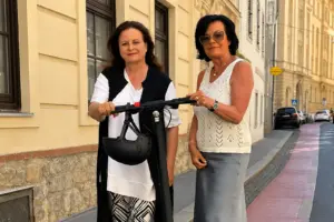 Zwei Frauen stehen mit einem E-Scooter auf einem Radweg