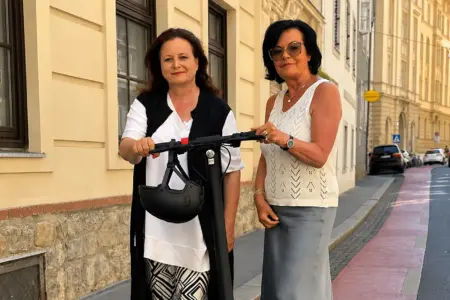 Zwei Frauen stehen mit einem E-Scooter auf einem Radweg
