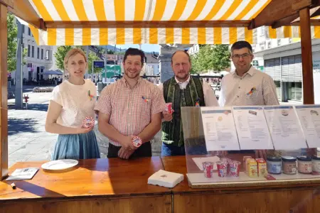 Eine Frau und drei Männer an einem Marktstand