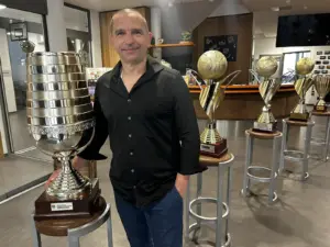 Ein Mann steht vor einem Sportpokal.