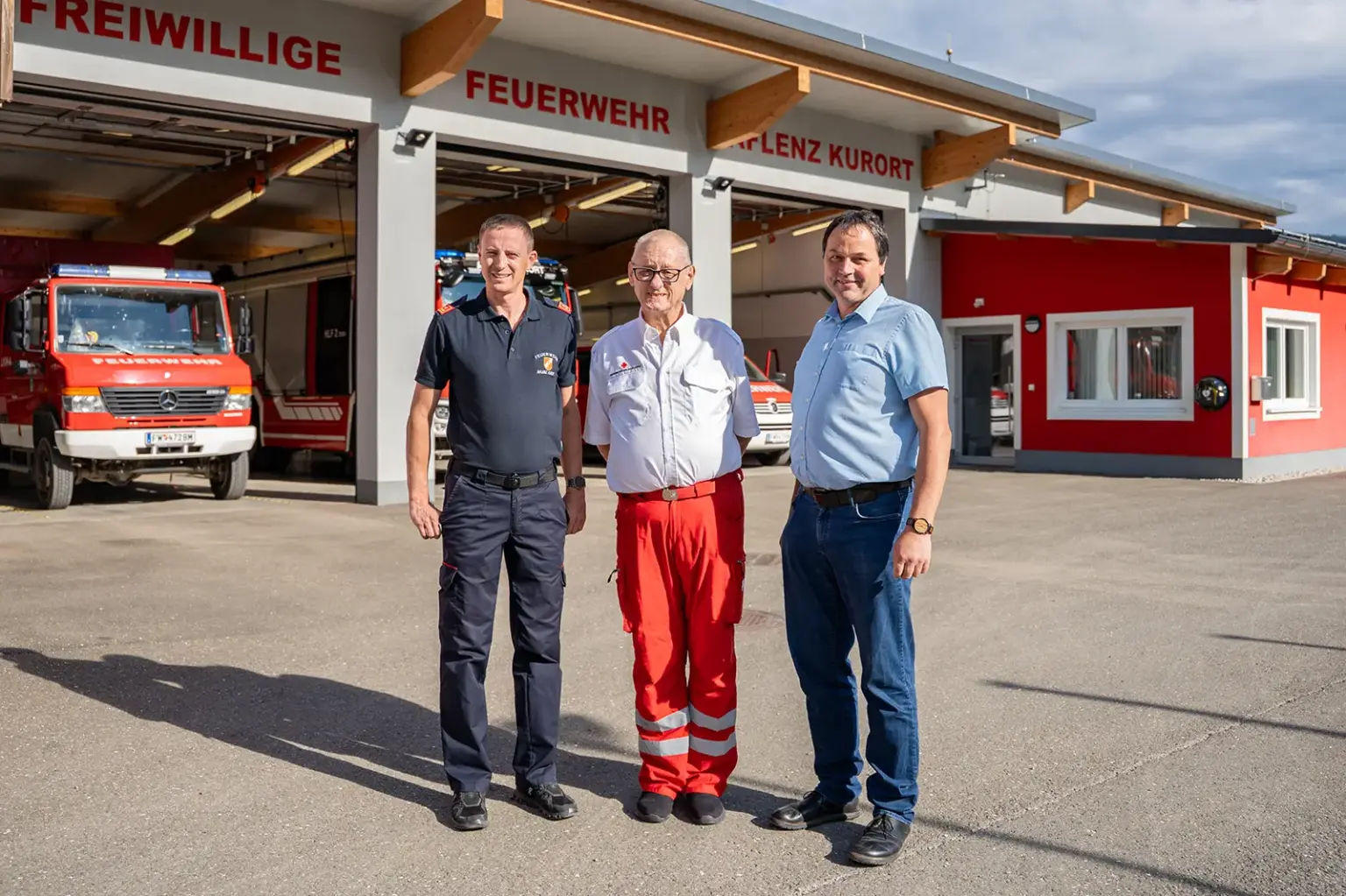 Blutspendeaktion in Aflenz Drei Männer stehen vor einem großen Haus mit mehreren Garagen voller Feuerwehrfahrzeuge