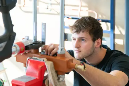 Drei Kapfenberger Berufs-Champions Ein Handwerker vermisst ein Werkstück, Messinstrument angelegt, ein Auge geschlossen