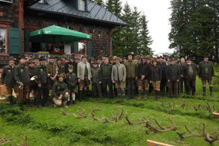 Abwurfstangenschau auf der Turnaueralm Eine große Gruppe von Personen in jagdlicher Kleidung steht auf einer Wiese vor einer Reihe von Geweihen