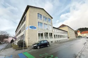 50 Löcher zum Check der Brucker Mittelschule Ein dreigeschoßiges Gebäude, darauf eine Tafel mit der Aufschrift "Mittelschule Bruck an der Mur"