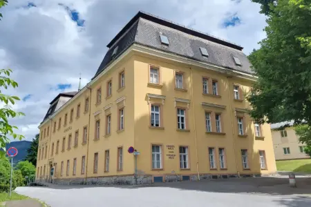 Musikschule Bruck: Grünes Licht für Dachsanierung Ein altes Schulgebäude mit gelber Fassade