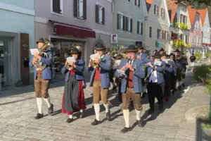 Eine Musikkapelle marschiert spielend durch die Straße einer Stadt.