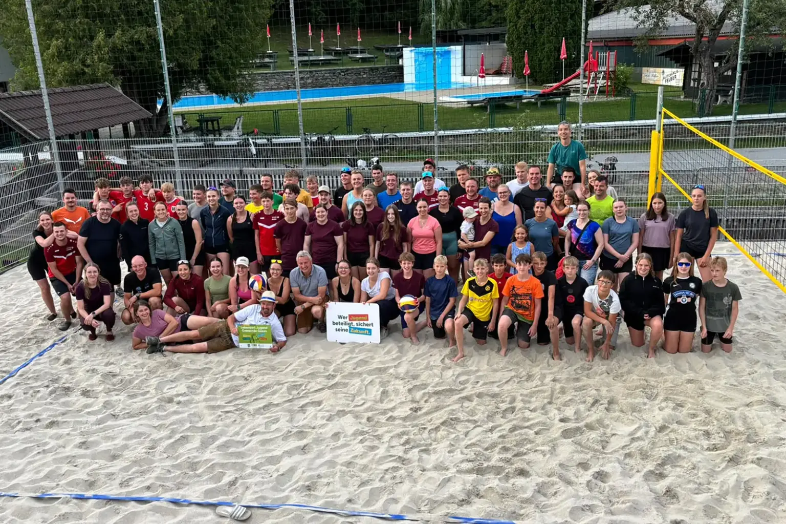 Beachvolleyballplatz in Gasen eröffnet Eine große Gruppe von Personen posiert auf einem Sandplatz mit einem großen Netz