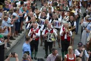 Eine Gruppe von Musikanten marschiert spielend durch eine Straße, gesäumt von zahlreichen ZuschauerInnen