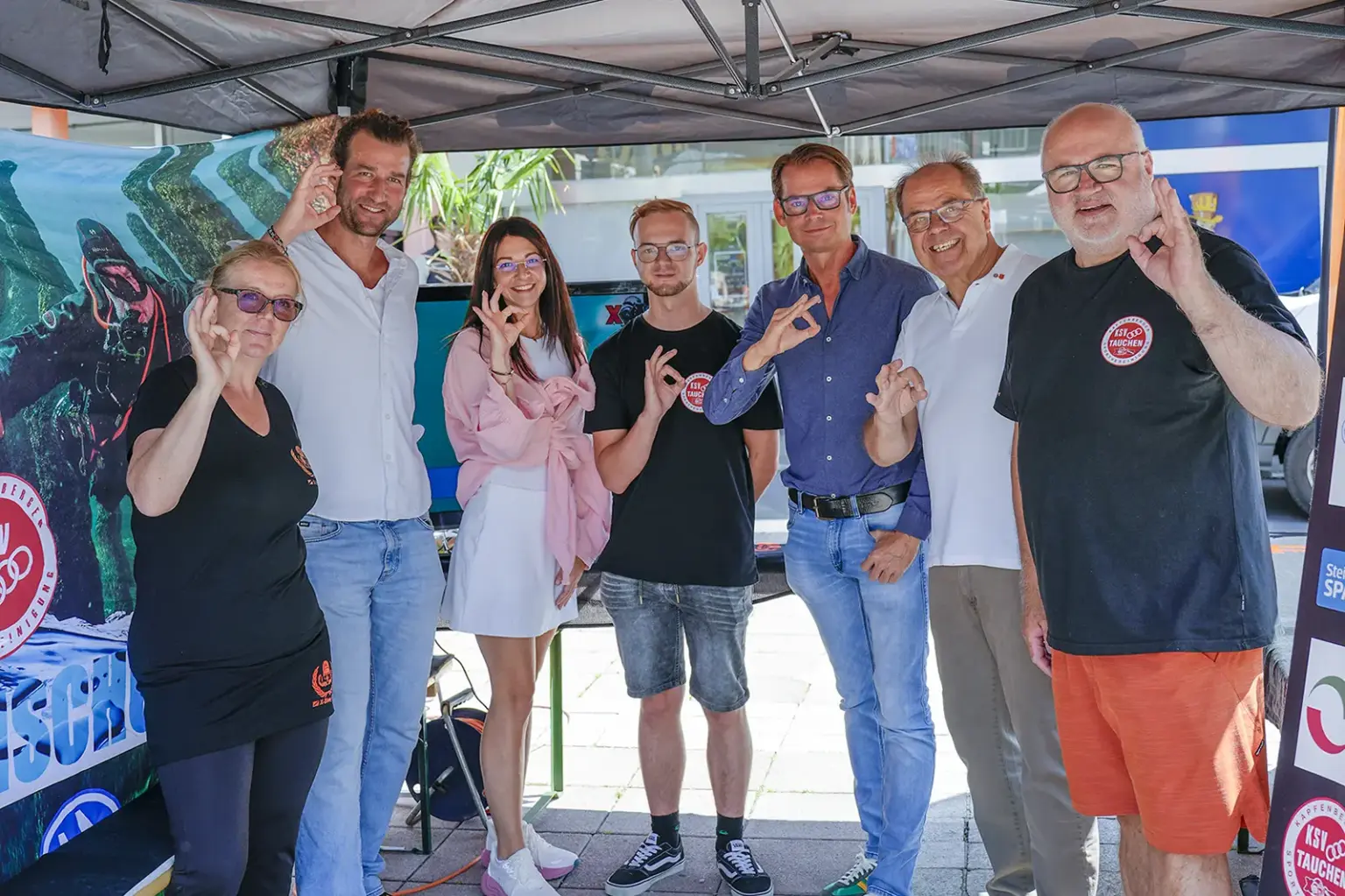 Sieben Personen stehen in einem Messepavillon