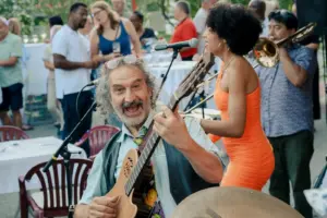Ein E-Gitarrenspieler und eine Sängerin musizieren live in einem Gastgarten