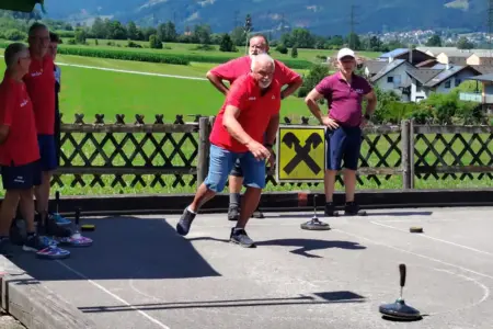 Mehrere Männer beim Stockschießen auf einer Asphaltbahn