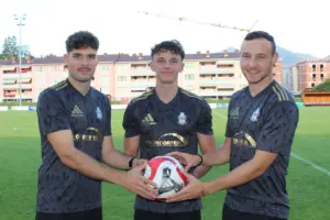 Drei Fußballer halten einen Ball.