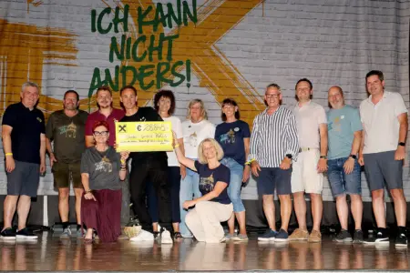 Eine Gruppe Menschen bei einer Scheckübergabe auf einer Bühne