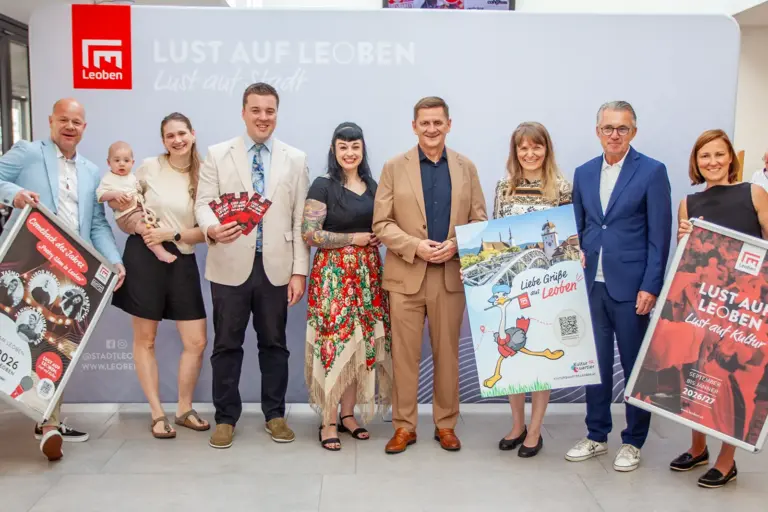 Vorschau auf den Kulturherbst in Leoben Vier Frauen, eine davon mit Baby auf dem Arm, und vier Männer stehen nebeneinander, vier von ihnen halten Folder und Plakate ins Bild