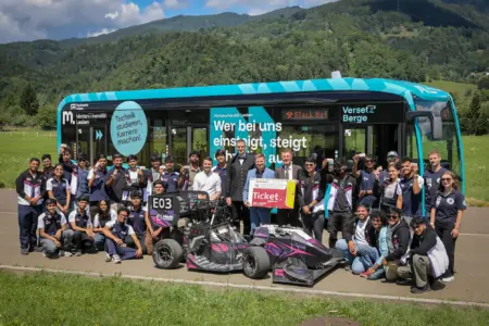 Studierende aus Indien in Leoben Eine große Gruppe von Personen posiert mit einem Rennwagen vor einem Bus