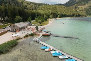 Ein Holzgebäude an einem Seeufer mit Tretbooten und einem Steg