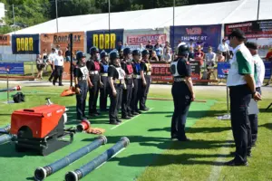 Eine Gruppe von Frauen in Feuerwehruniformen steht neben diversen Geräten auf einer Wiese