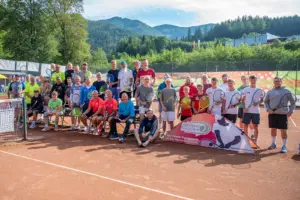 Eine Gruppe von rund 40 Männern mit Tennisschlägern auf einem Tennisplatz