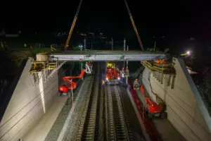 Eine Brückenbaustelle bei Nacht, das Bauwerk überspannt eine Eisenbahnstrecke