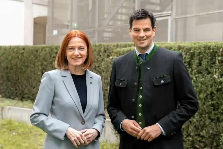 Eine Frau und ein Mann stehen vor einer Hecke
