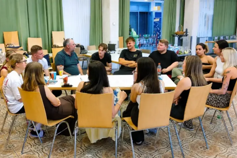 St. Barbara: Europadialog in der Schule Eine Gruppe von Jugendlichen sitzt mit einem Erwachsenen um einen Tisch
