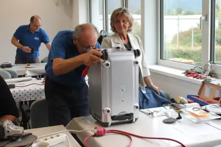 St. Michael: Repaircafé feiert zehnten Geburtstag Ein Mann arbeitet an einem Gerät, eine Frau sieht im dabei zu