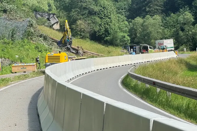 Steinschlagschutz an der B20 zwischen Thörl und Kapfenberg Eine durch eine Betonleitwand längs geteilte Straße, im Hintergrund Baumaschinen