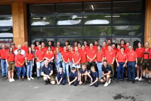 Eine Gruppe von rund 50 Personen, großteils in roten T-Shirts, vor einem Hallentor.