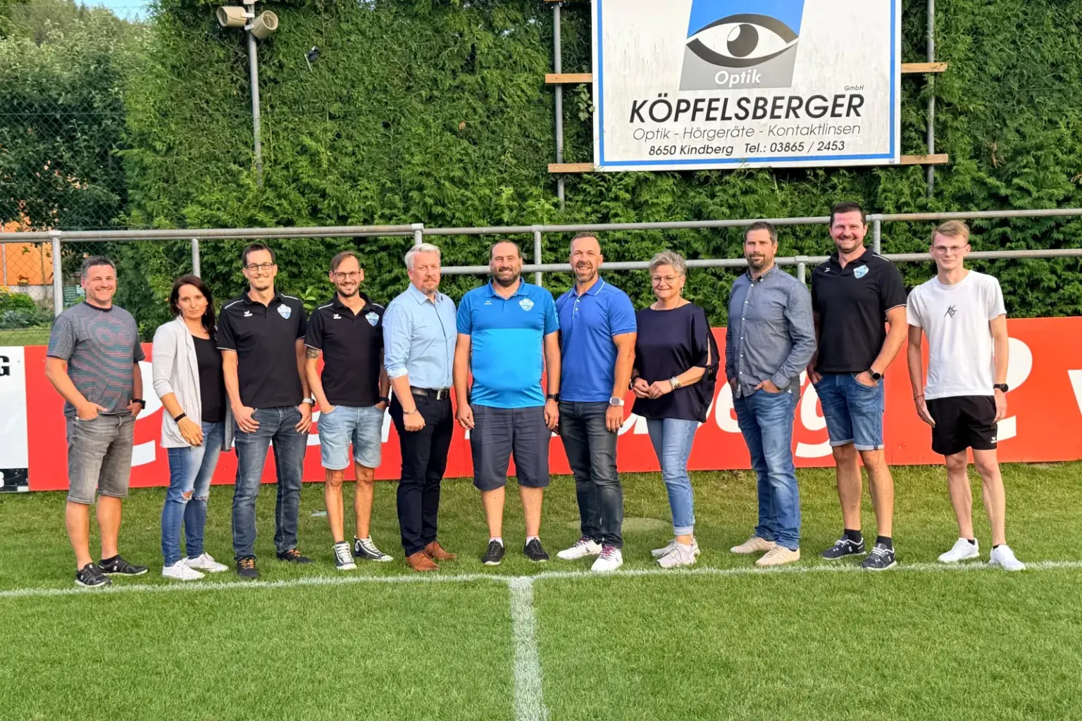 Neuer Name und neuer Obmann bei den Kindberger Fußballern Elf Personen stehen auf einem Fußballfeld.
