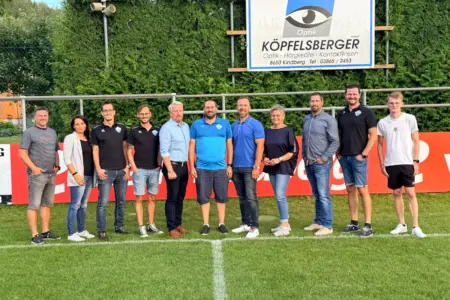 Neuer Name und neuer Obmann bei den Kindberger Fußballern Elf Personen stehen auf einem Fußballfeld.