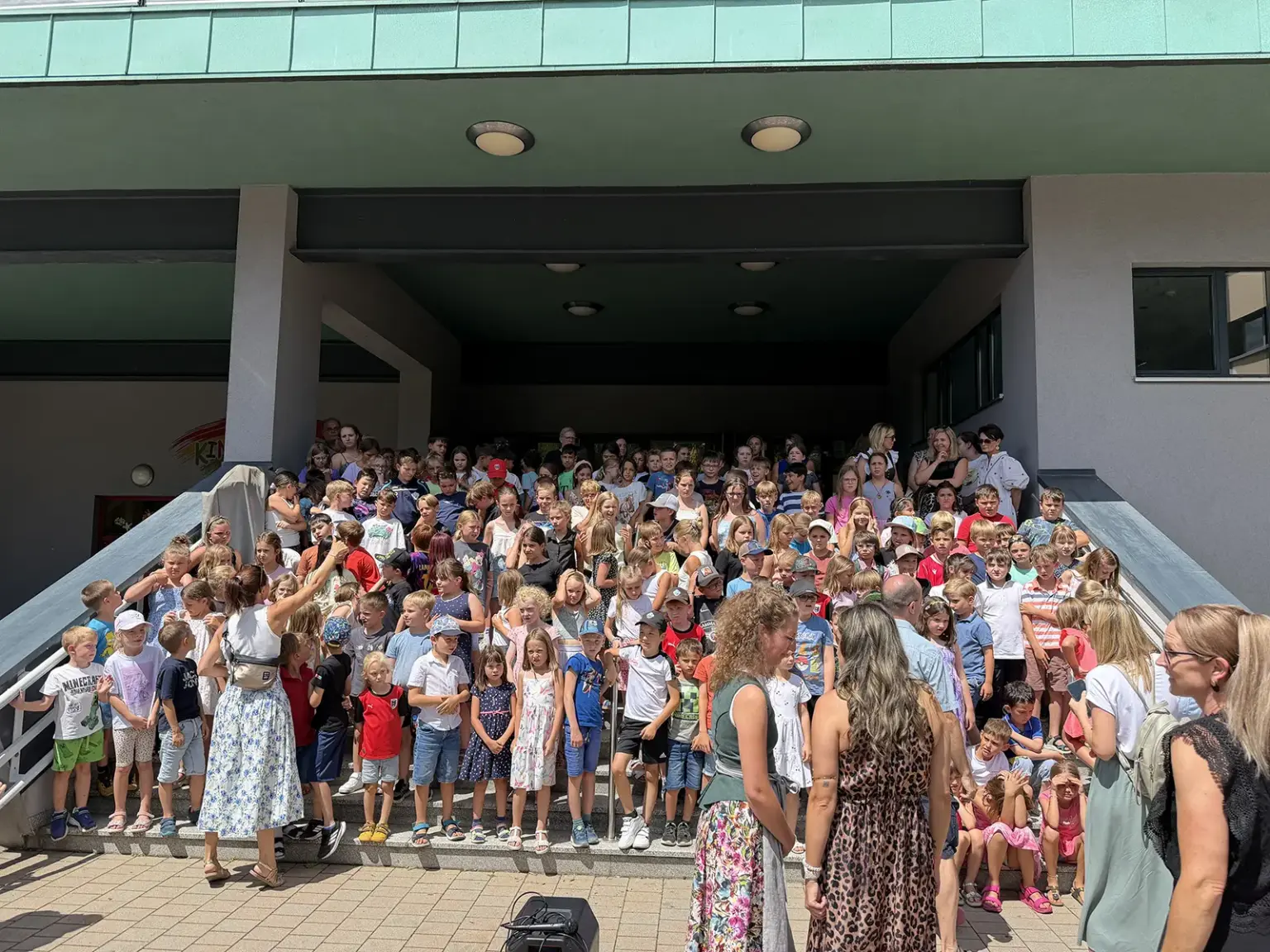 Eine große Gruppe an Schulkindern nimmt auf einer Treppe Aufstellung.