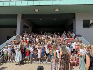„Kleine Hände – große Kunst“ Eine große Gruppe an Schulkindern nimmt auf einer Treppe Aufstellung.