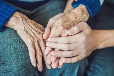 Die Hände einer jungen Person halten die Hände einer betagten Person