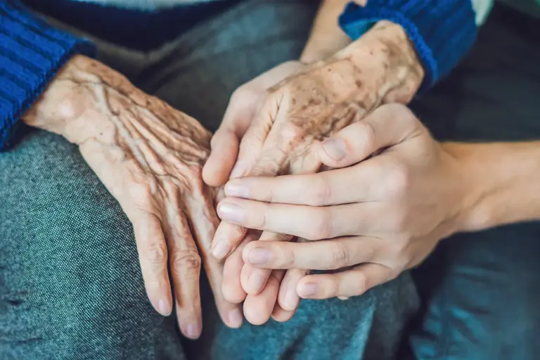 Die Hände einer jungen Person halten die Hände einer betagten Person
