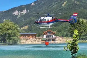 Ein Hubschrauber holt Löschwasser aus einem Teich