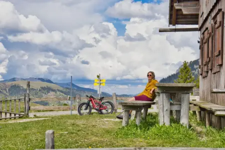 Hochsteiermark: Tipps für Radler und Wanderer Eine Frau sitzt neben einem Fahrrad vor einer Almhütte