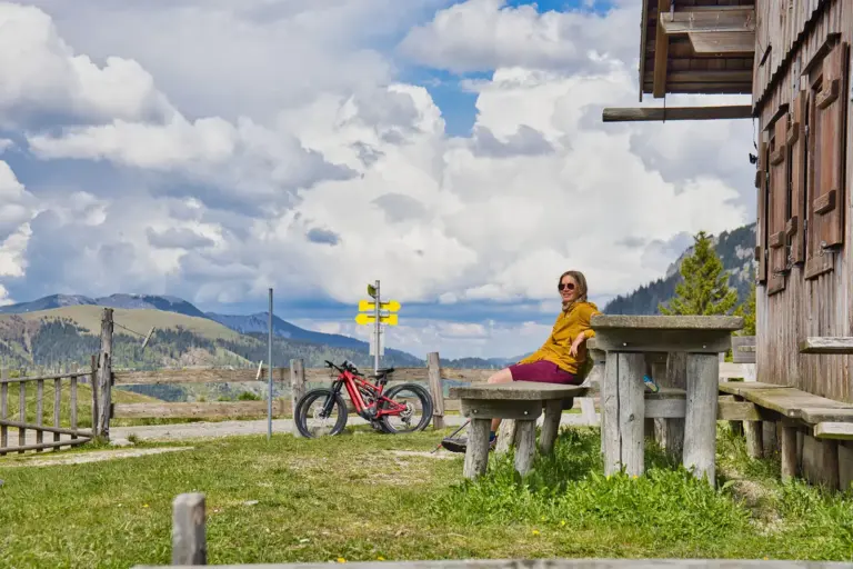 Hochsteiermark: Tipps für Radler und Wanderer Eine Frau sitzt neben einem Fahrrad vor einer Almhütte