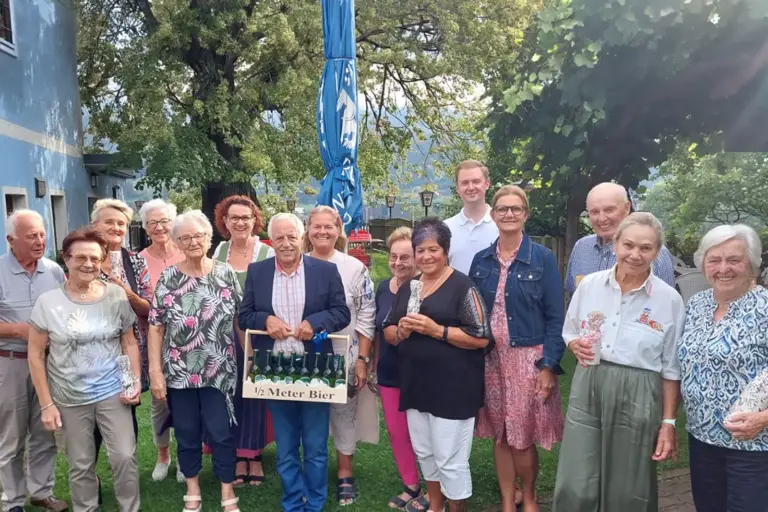 Eine Gruppe von älteren Menschen steht mit Geschenken auf einer Wiese