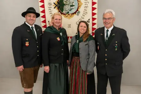 Ein Frauenreferat für den ÖKB Bruck Zwei Männer und zwei Frauen in Tracht stehen vor einer Fahne