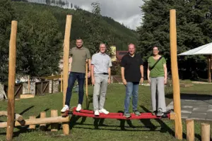 Drei Männer und eine Frau stehen auf einem Klettergerüst auf einem Spielplatz