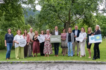 Grazer Bergland: Zehn Millionen für 36 Projekte Eine Gruppe von Personen mit mehreren Tafeln steht auf einer Wiese