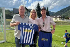 Zwei Männer und eine Frau halten eine Fußballdress