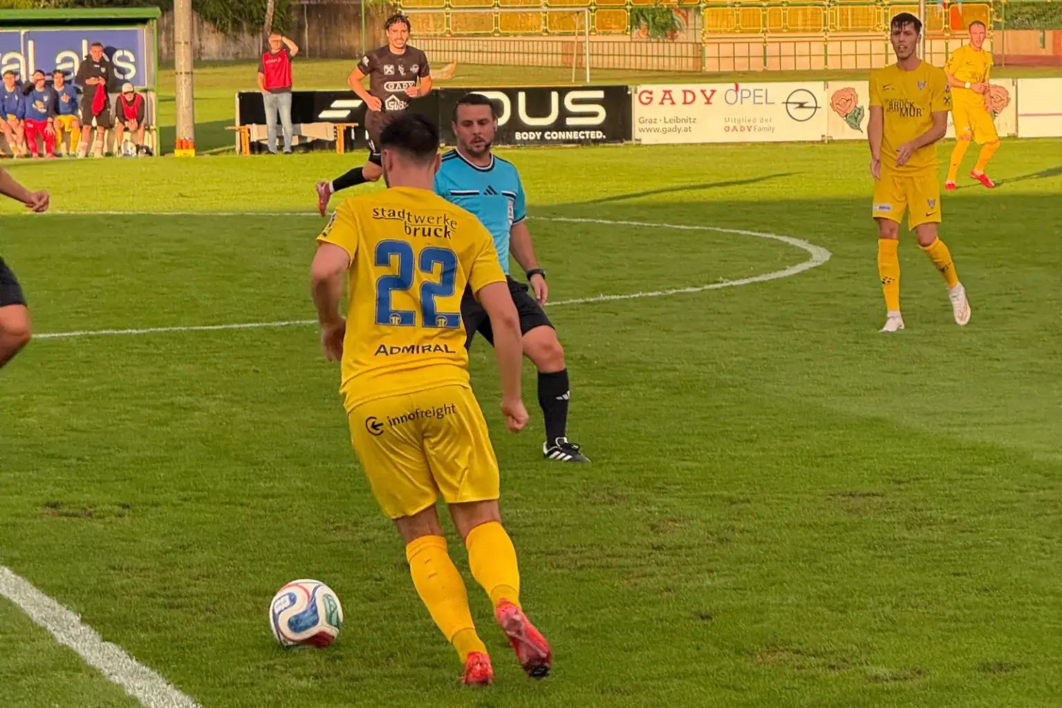 Ein Fußballer mit der Nummer 22. Dahinter ein Schiedsrichter.