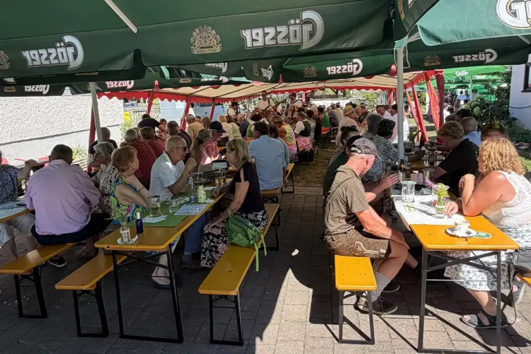 Bestens besuchtes Gartenfest in Kammern Eine große Gruppe von Personen sitzt an Biertischen unter Sonnenschirmen